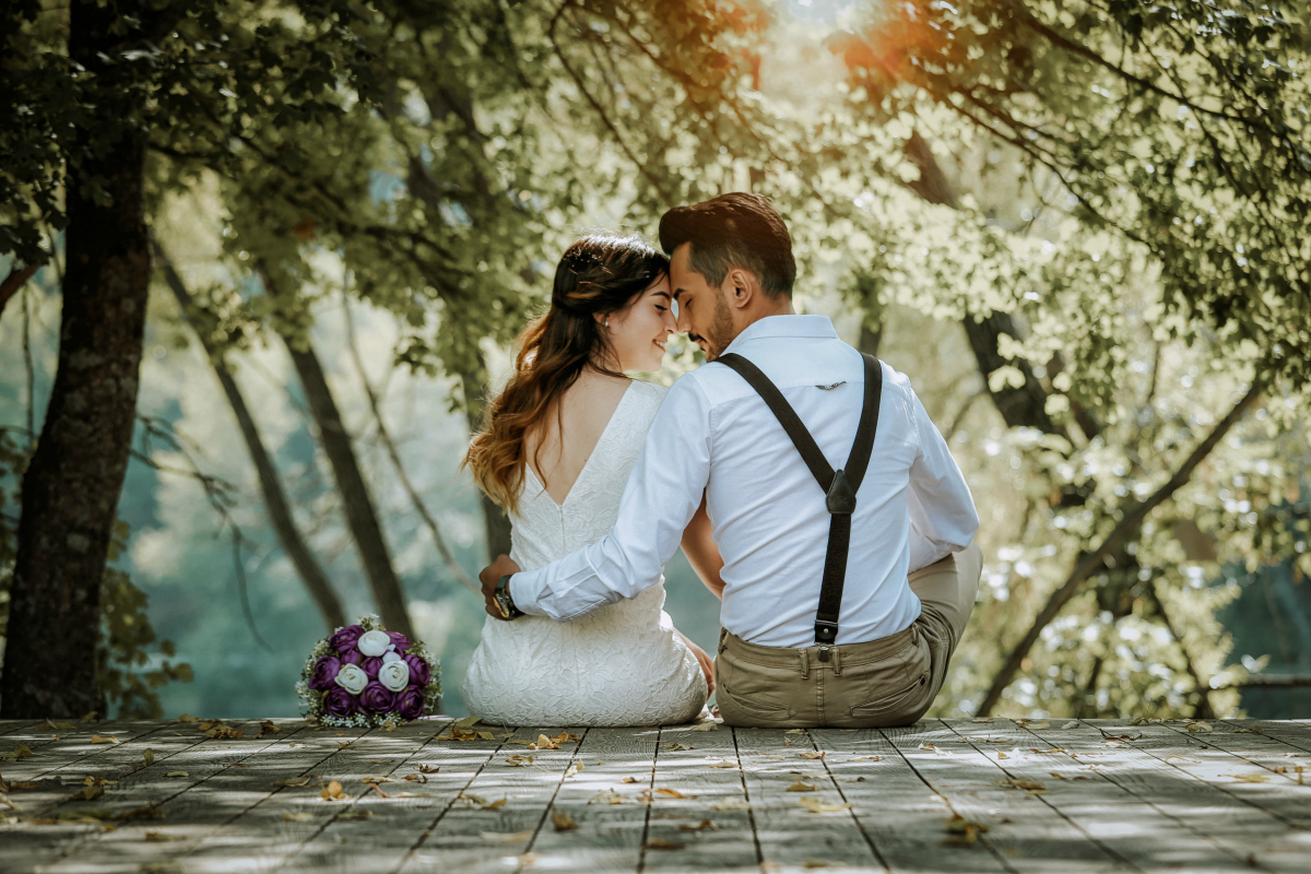 wedding couple sitting on bridge