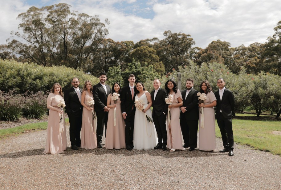 bridal party with bride and groom lined up on road in front of trees - wedding ideas on a budget