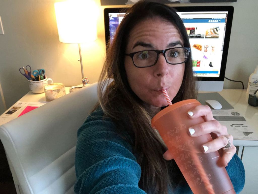 woman sipping from orange straw cup