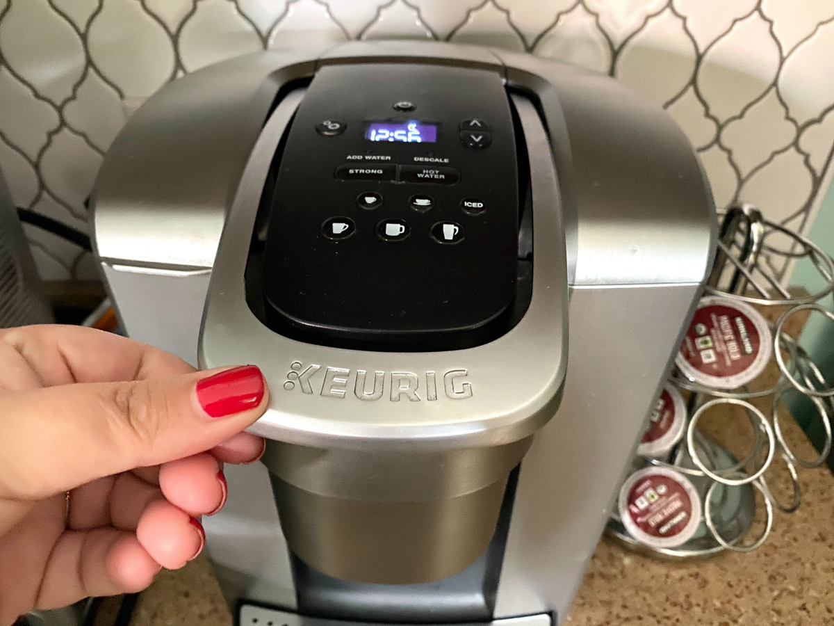 hand touching Keurig brewer