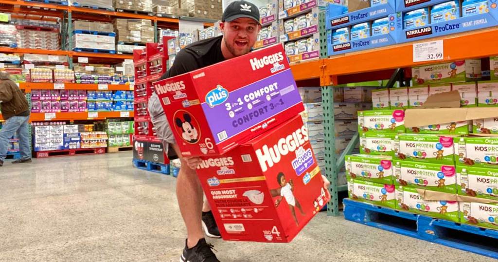 man holding club size boxes of Huggies diapers