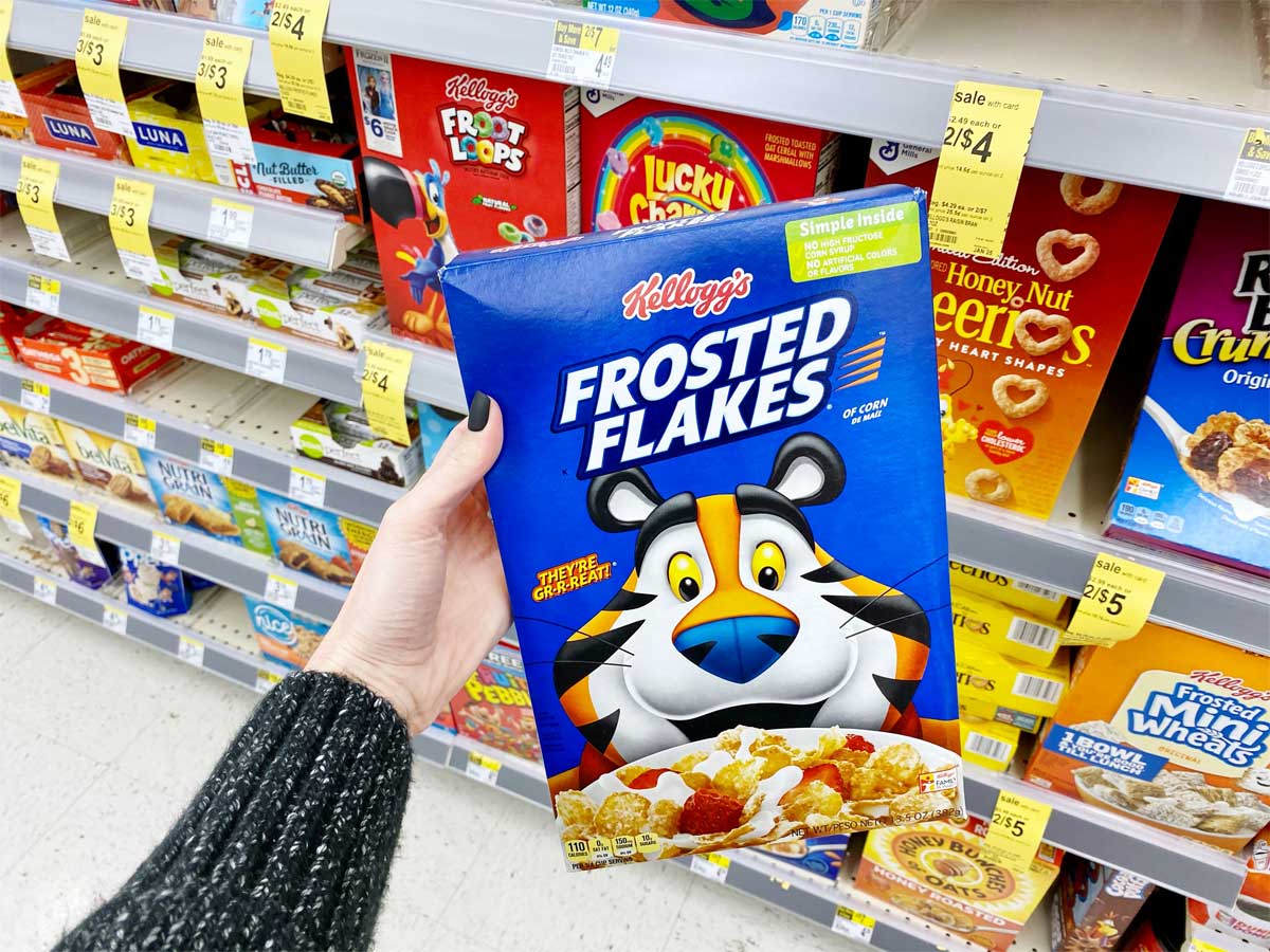 hand holding a box of brand name cereal in a store