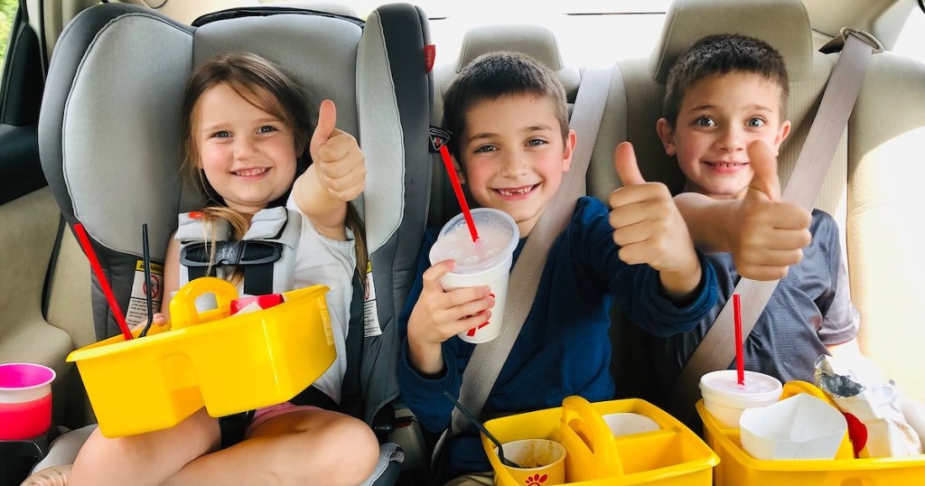 kids in car with yellow school caddies on laps with chick fila food inside