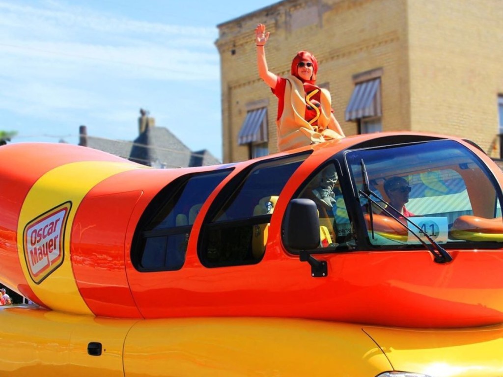 man in hot dog costume riding on Weinermobile