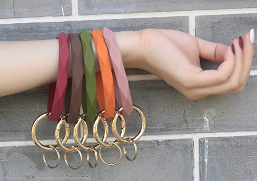 arm holding matte colored silicone rings on wrist in front of brick wall