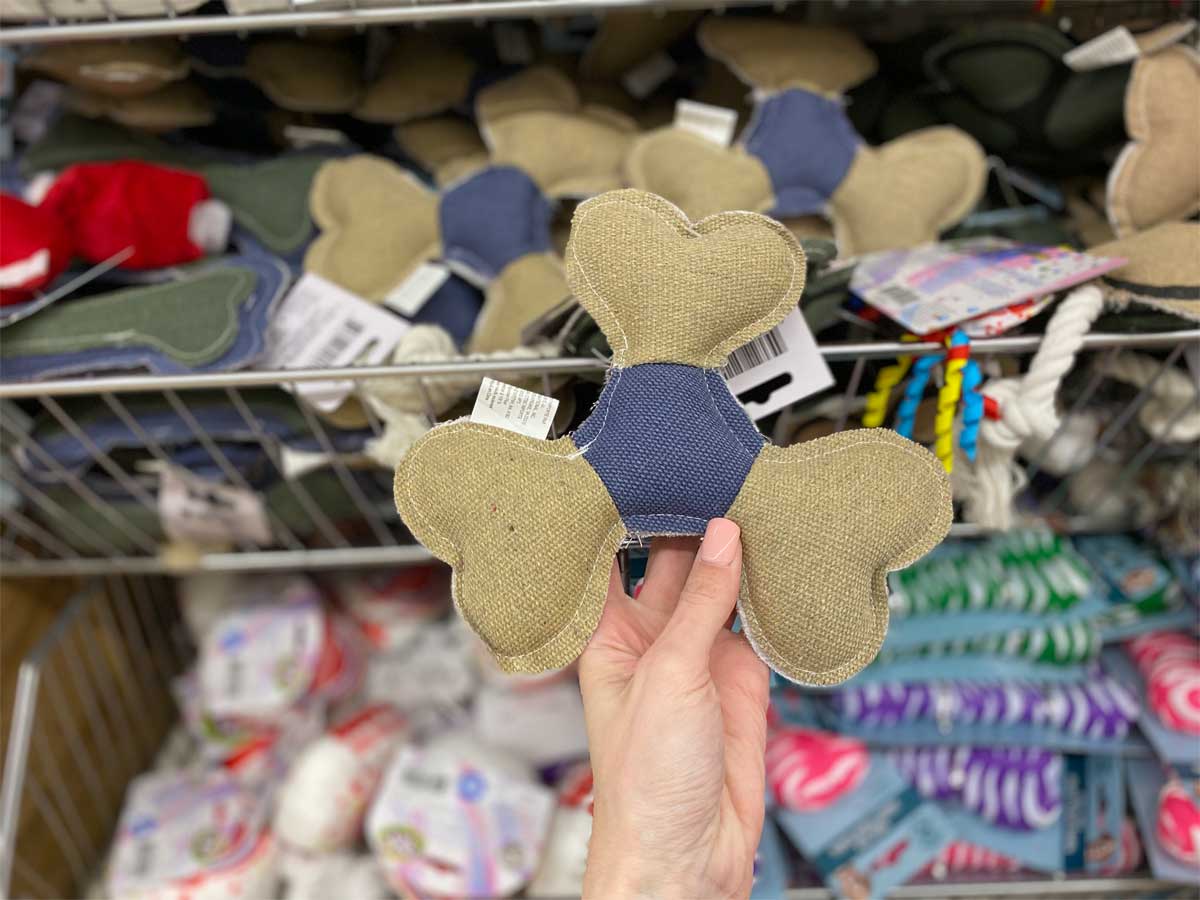 hand holding dog toy in front of store rack