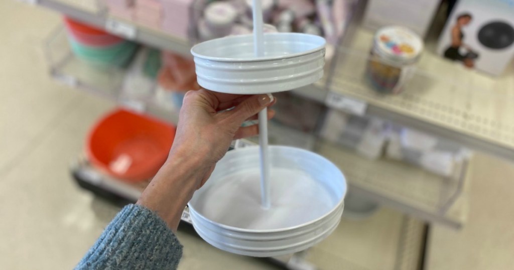 hand holding white two tiered metal serving tray in store