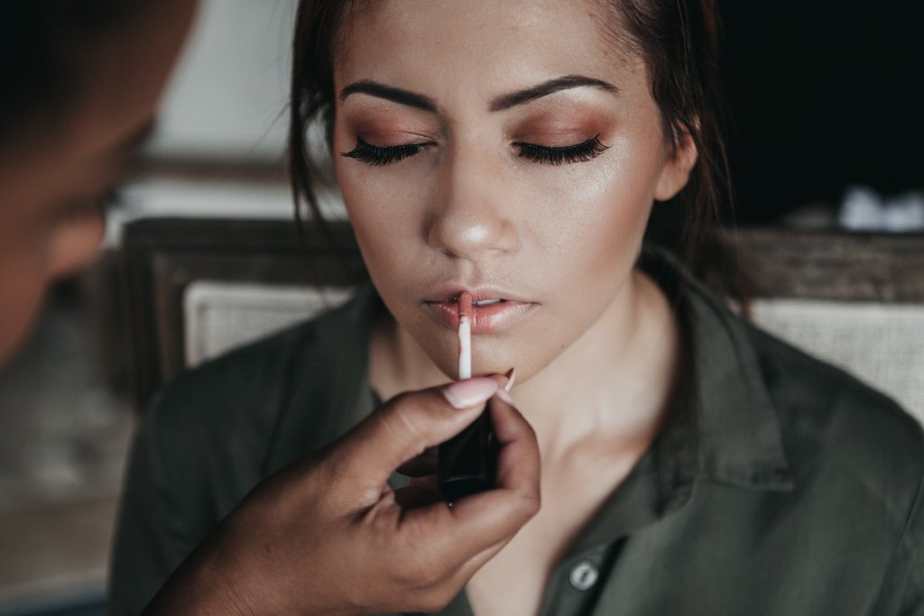 woman putting lip gloss on woman's face for wedding