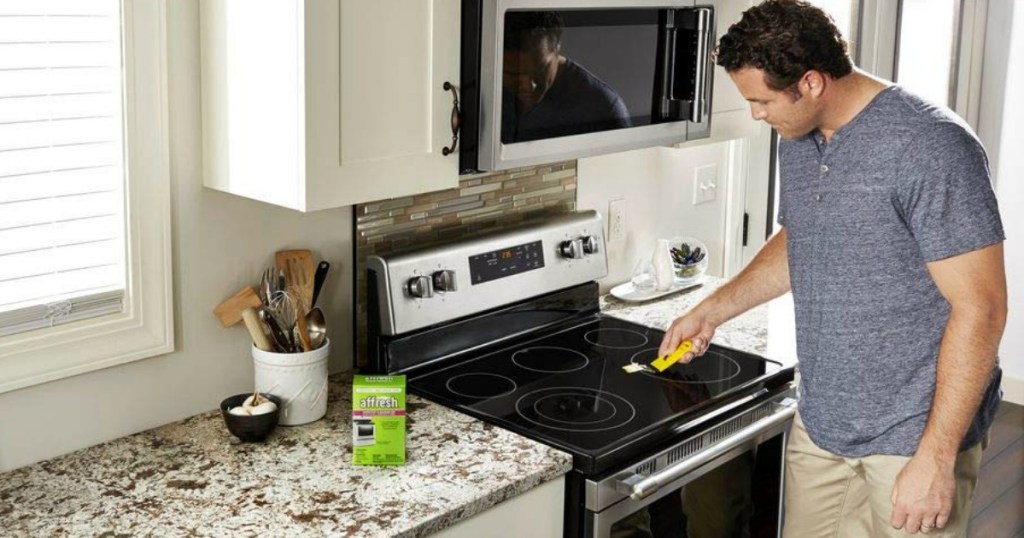 man in kitchen cleaning a stove