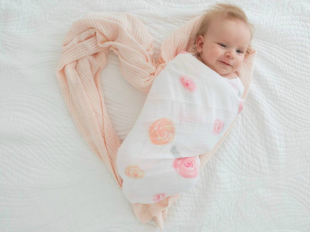 Baby wrapped in floral muslin blanket with additional blanket in heart shape