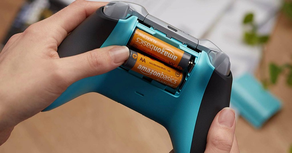 person putting 2 AA batteries into a video game controller