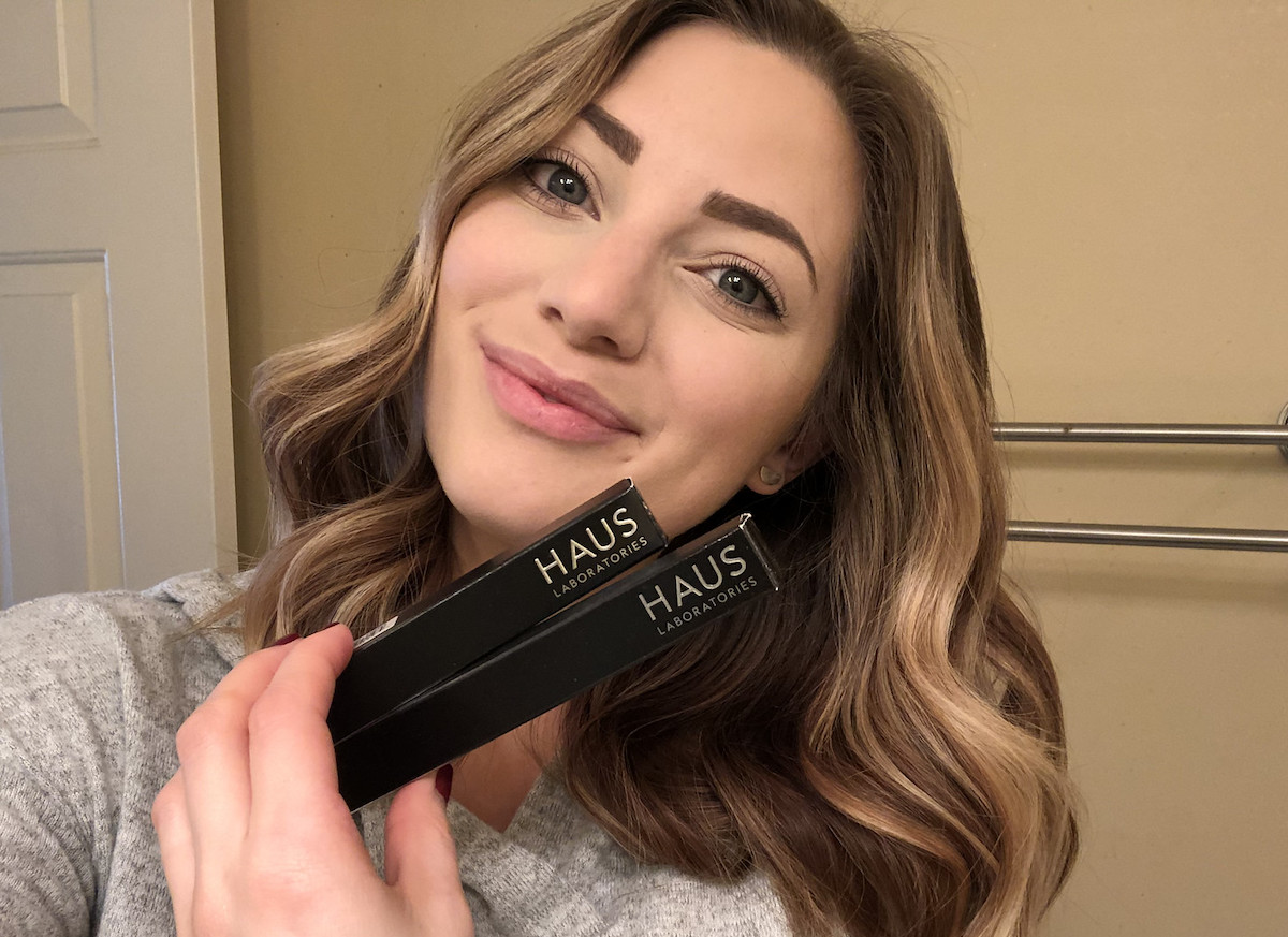 woman holding black makeup boxes smiling