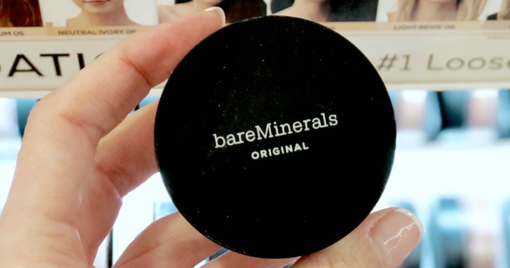 Woman's hand holding a round container of mineral foundation