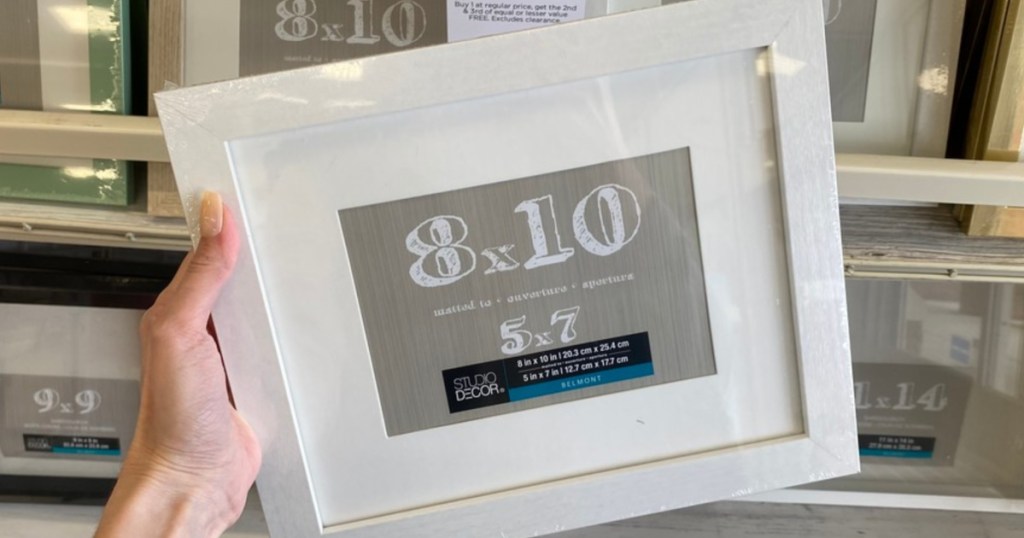 Woman's hand holding white frame in store