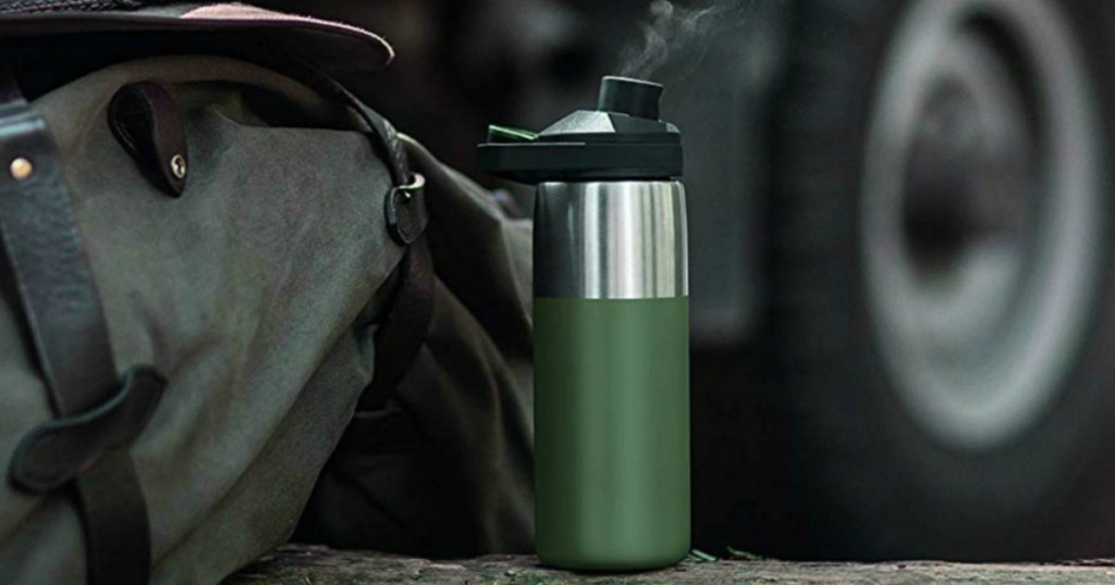 Large flask water bottle in olive green near bag and hat on ground