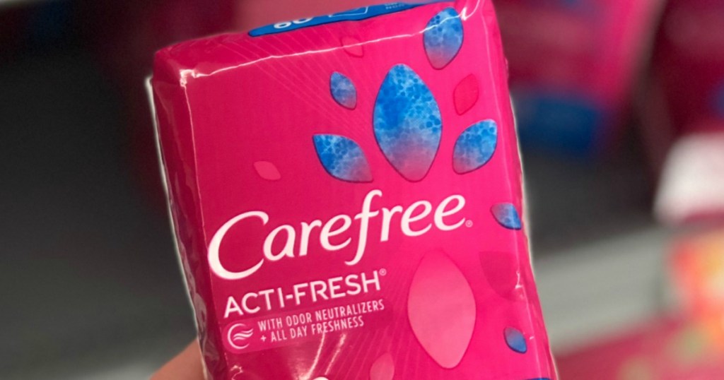 Hand holding a large pink package of panty liners in-store near shelf