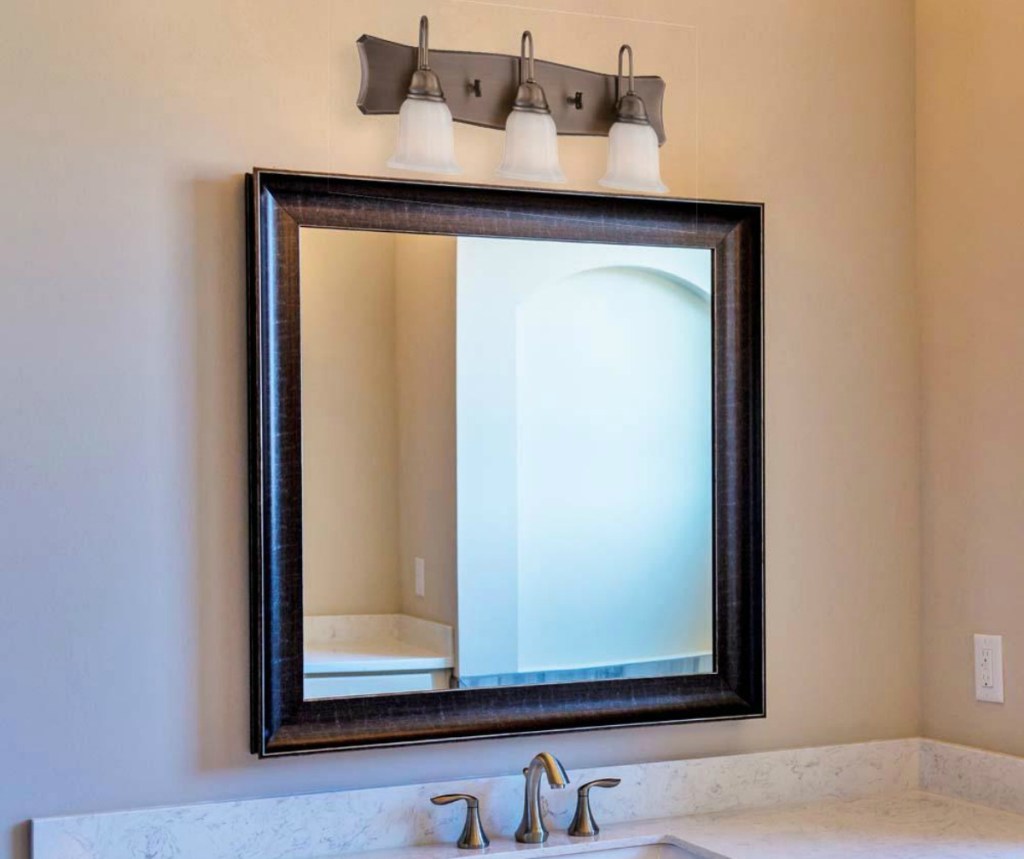 bronze light fixture with three sconces over bathroom sink