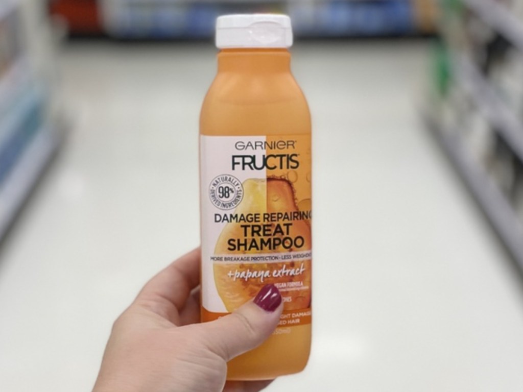 Woman holding shampoo bottle in store aisle