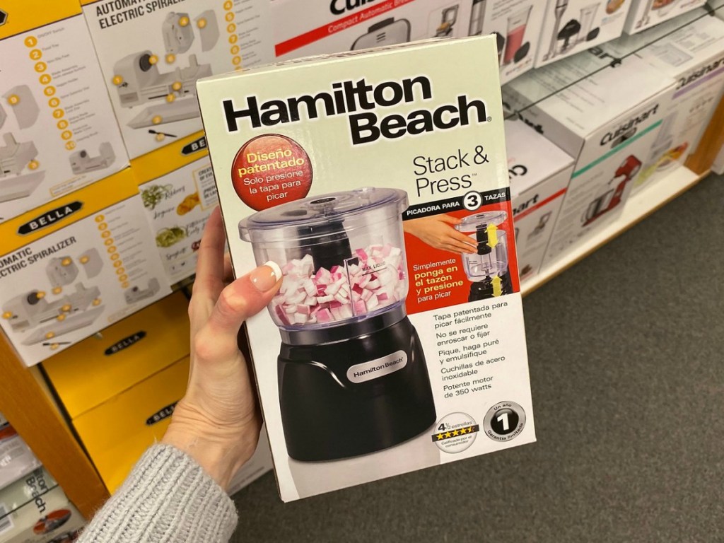 Hand holding box with mini food processor inside near in-store display