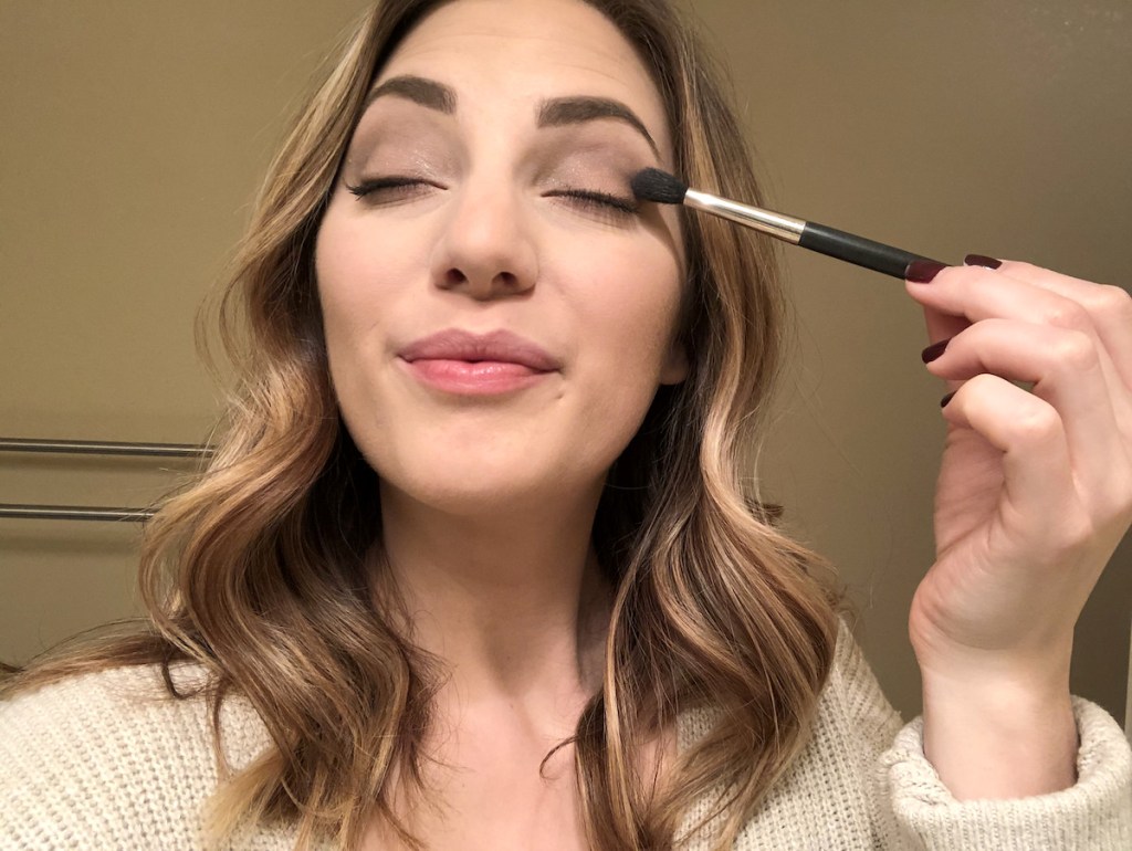 woman putting on makeup with brush