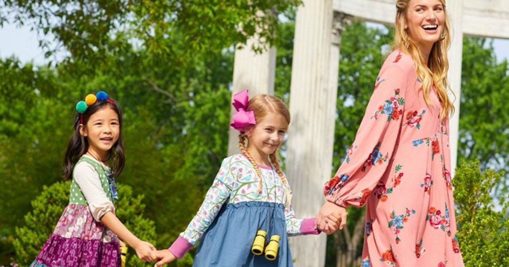 two girls and a woman holding hands while walking