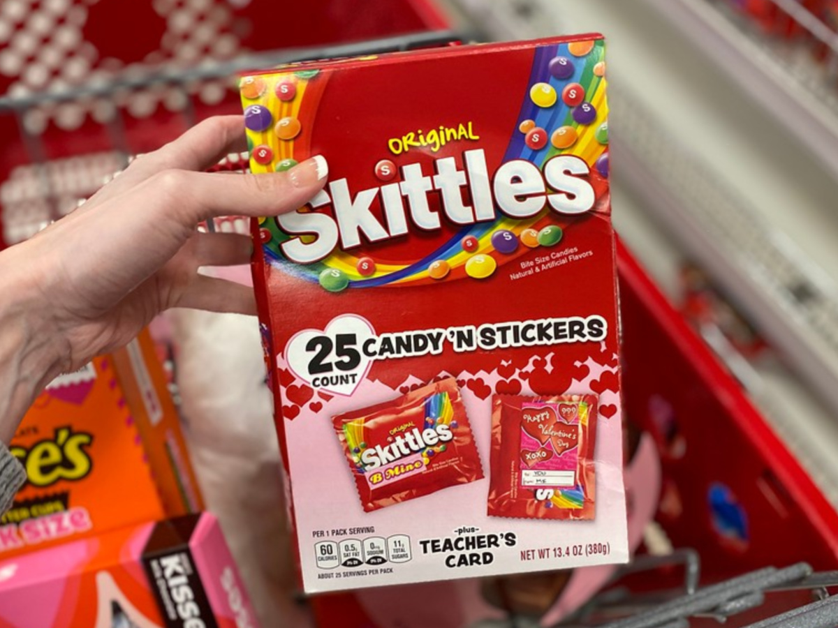 hand holding box of Valentine's Day Skittles and stickers