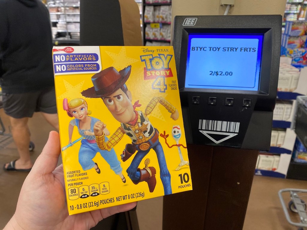 hand holding box of Toy Story fruit snacks by price scanner