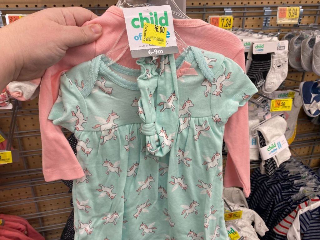 woman's hand holding three piece baby girl outfit at store 