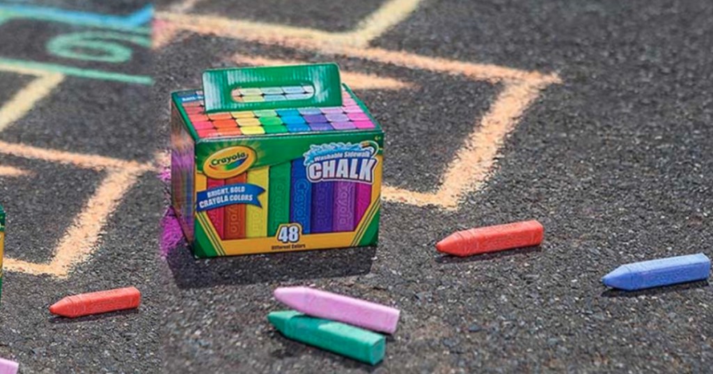 crayola sidewalk chalk box on pavement with chalk and drawings on pavement