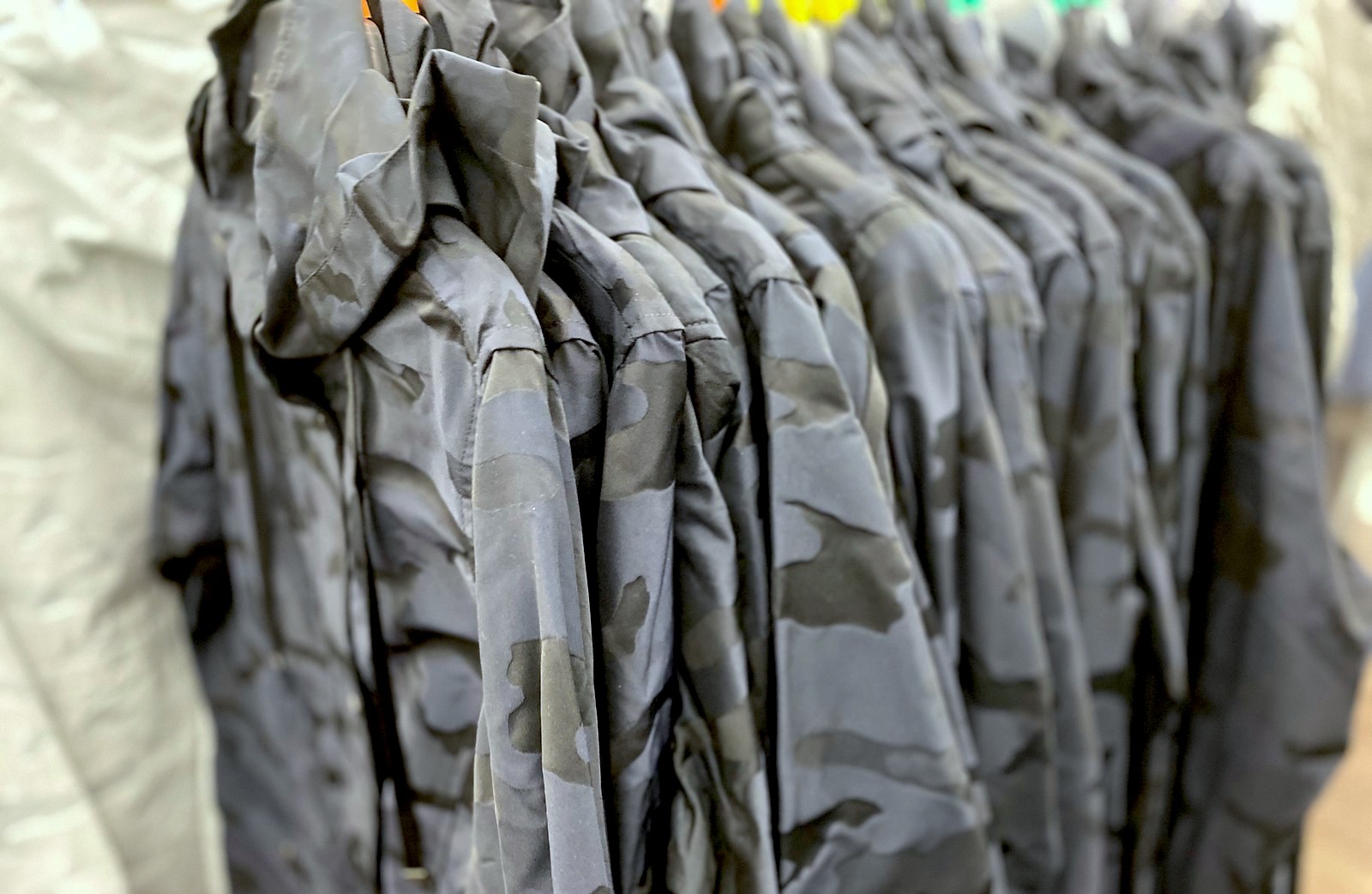 row of black and blue camo jackets hanging in store