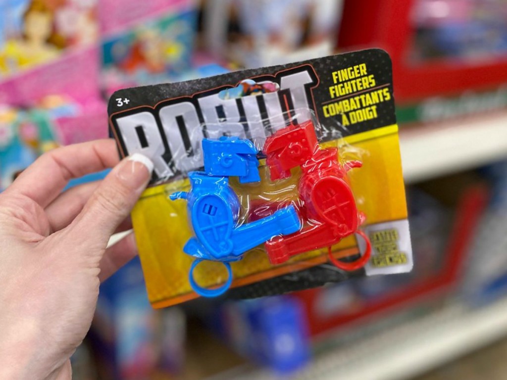 hand holding little package of toy robots by store display