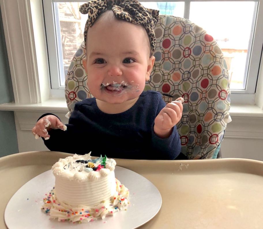 baby sitting in highchair eating white smash cake