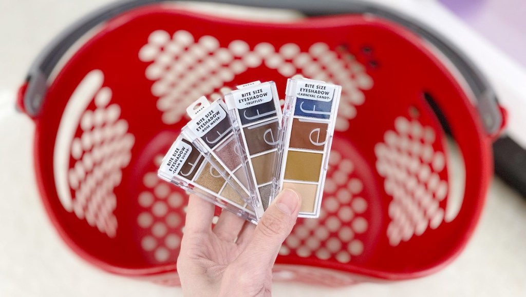 hand holding four different colors of shadow palettes with target basket in the background