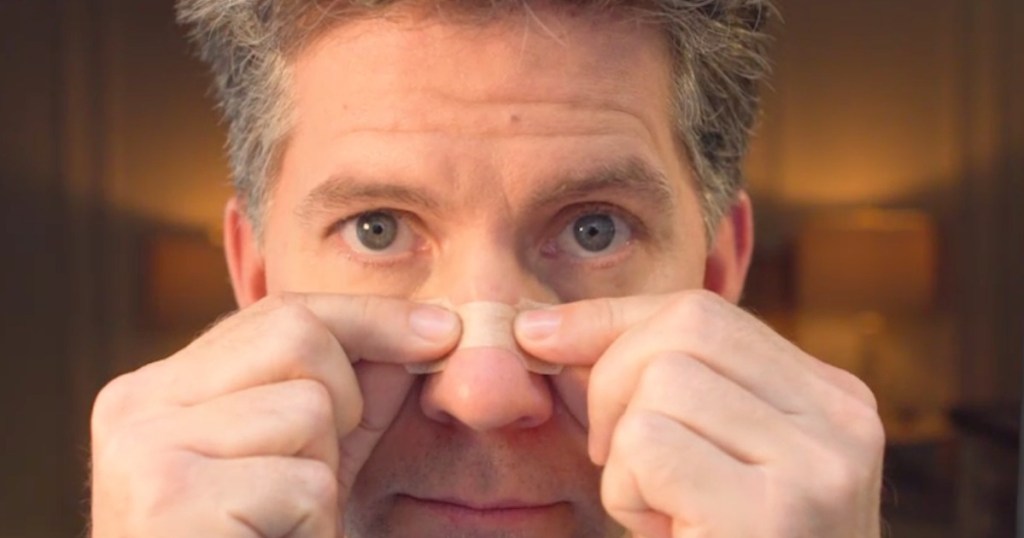 man putting a nasal strip on his nose