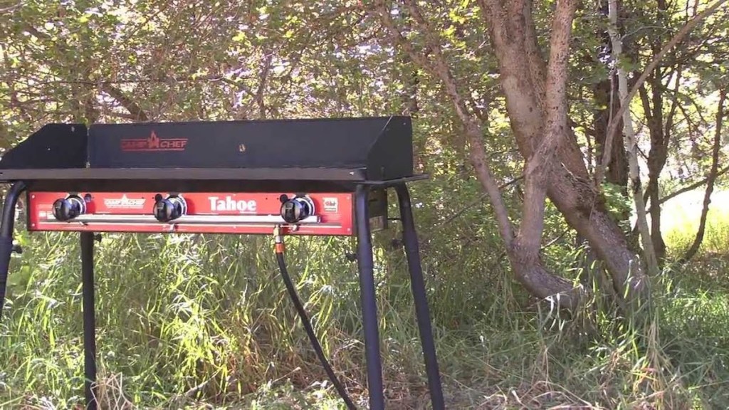 man cooking on Camp Chef Tahoe 3-Burner Propane Camp Stove with Griddle outside in the woods