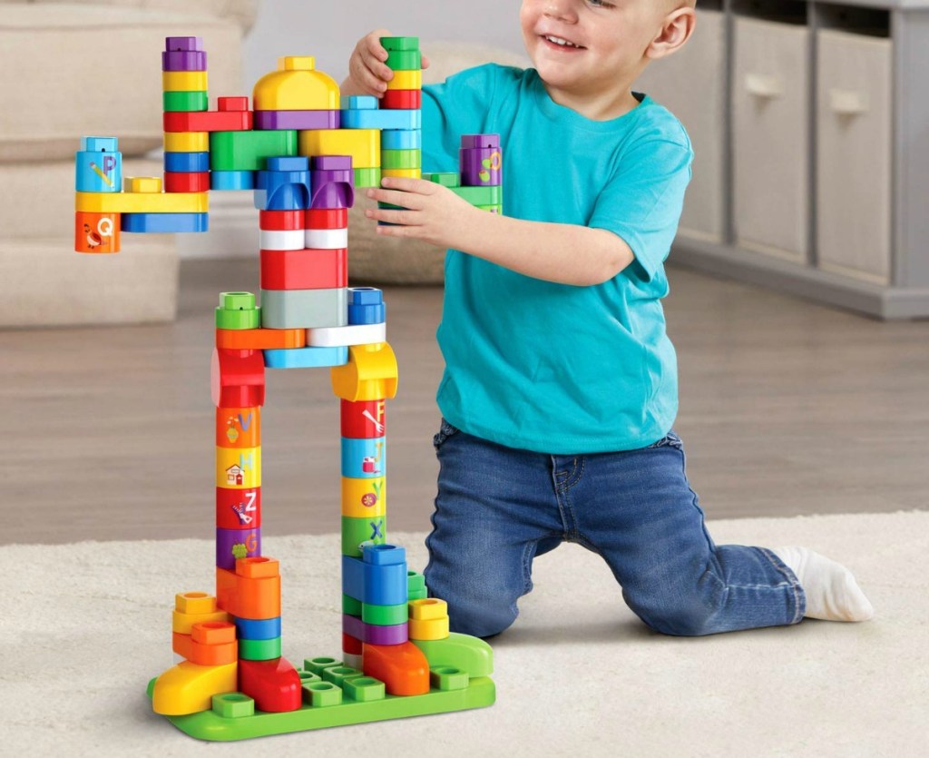 little boy playing with a large set of blocks on living room floor