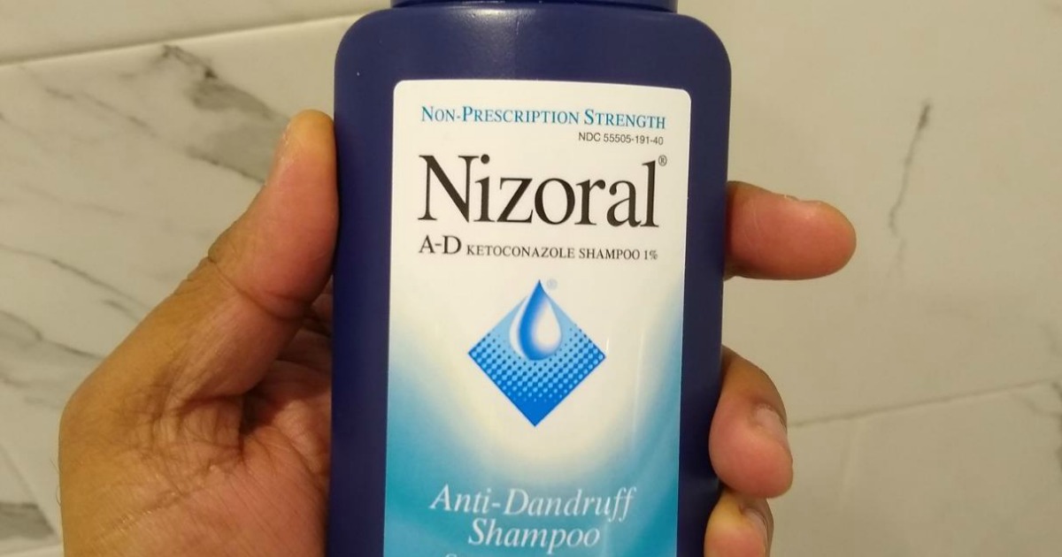 Hand holding Nizoral Shampoo