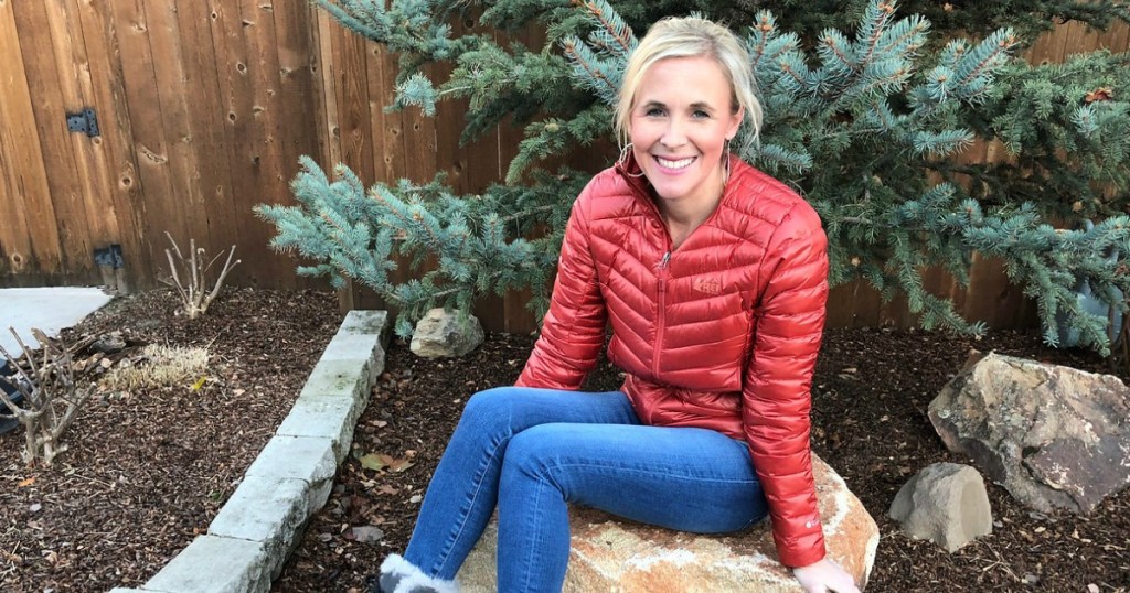 woman sitting on a rock wearing an orange jacket