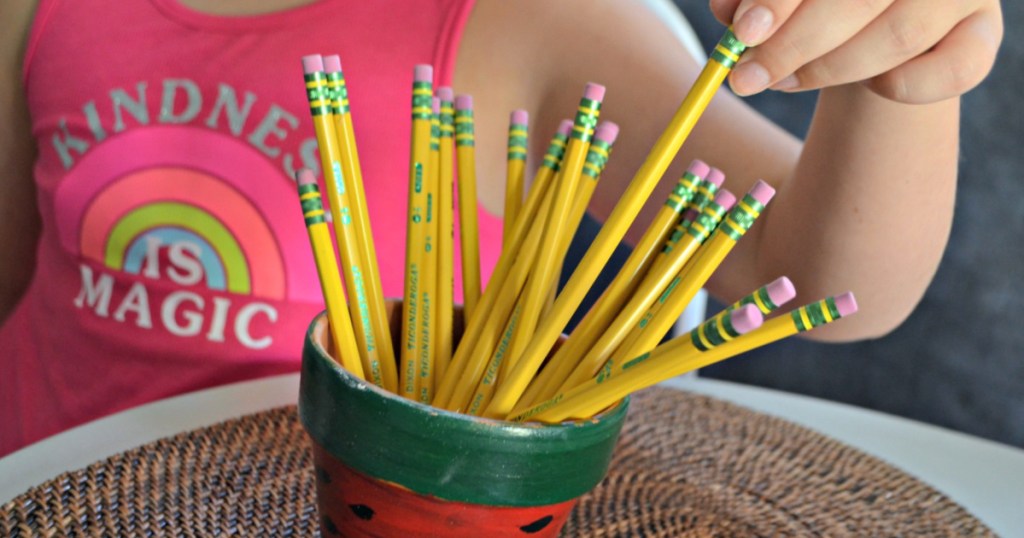 girl pulling pencil out of painted planter at table