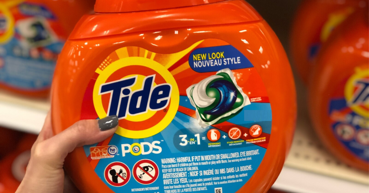 woman's hand holding laundry detergent pac container in store aisle