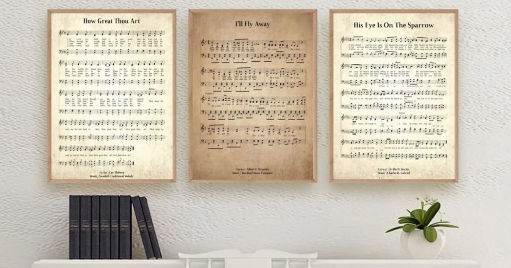 three large framed prints hanging over a piano with books on the left side and a plant on the right