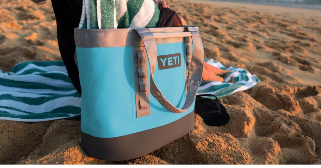 blue YETI bag holding blue and white towel and placed on sand