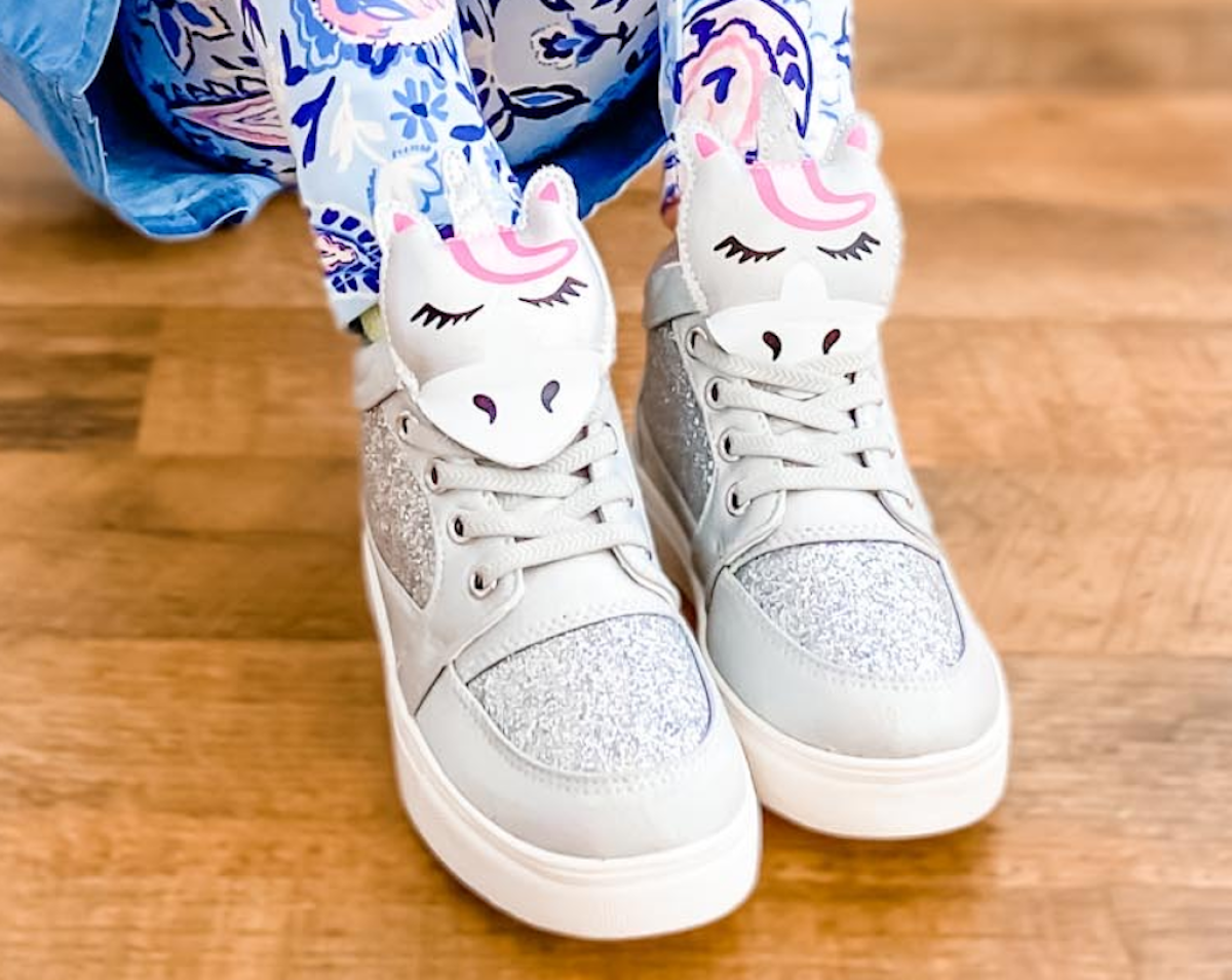 kid wearing unicorn shoes on hardwood floor