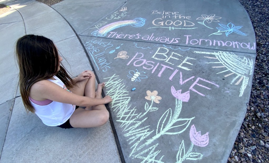 girl writing messages using sidewalk chalk