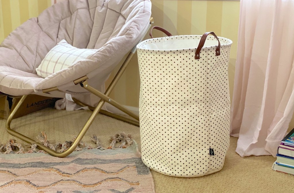 white polka dot clothes hamper sitting in room next to teen chair