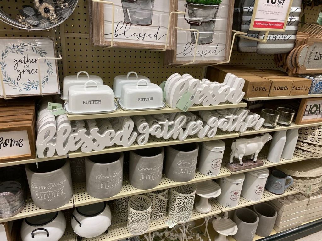 wall display at store offarm house style decor including butter dishes, wooden word signs and utensil holders