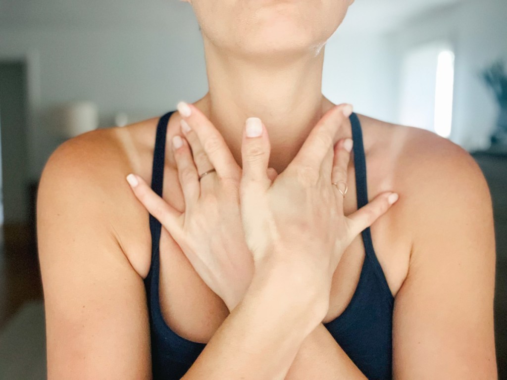 close of of womans crossed arms over chest applying pressure to lymphatic nodes on neck