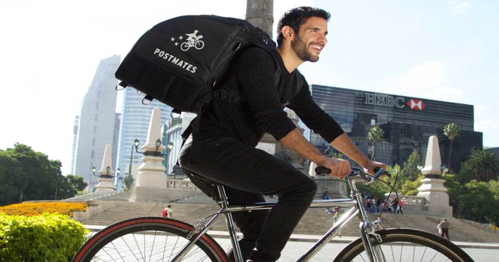 Man wearing Postmates backpack with bike