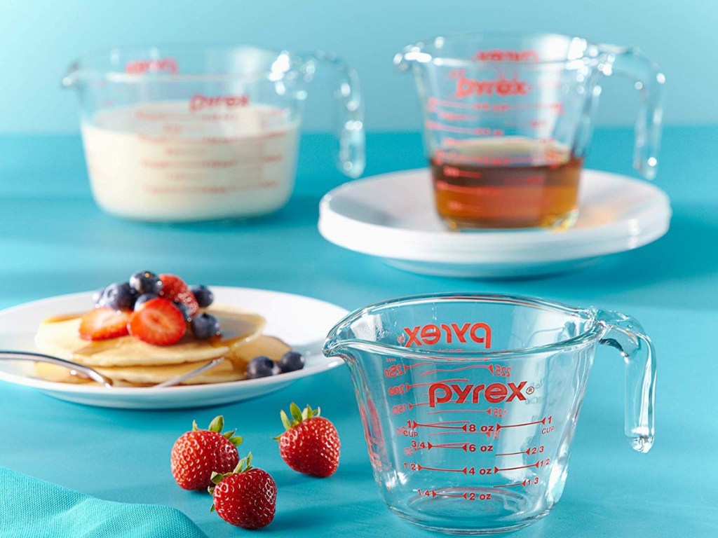 blue background with measuring cups, pancakes and strawberries