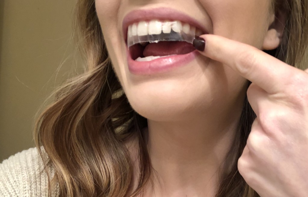 woman wearing whitening strip on teeth